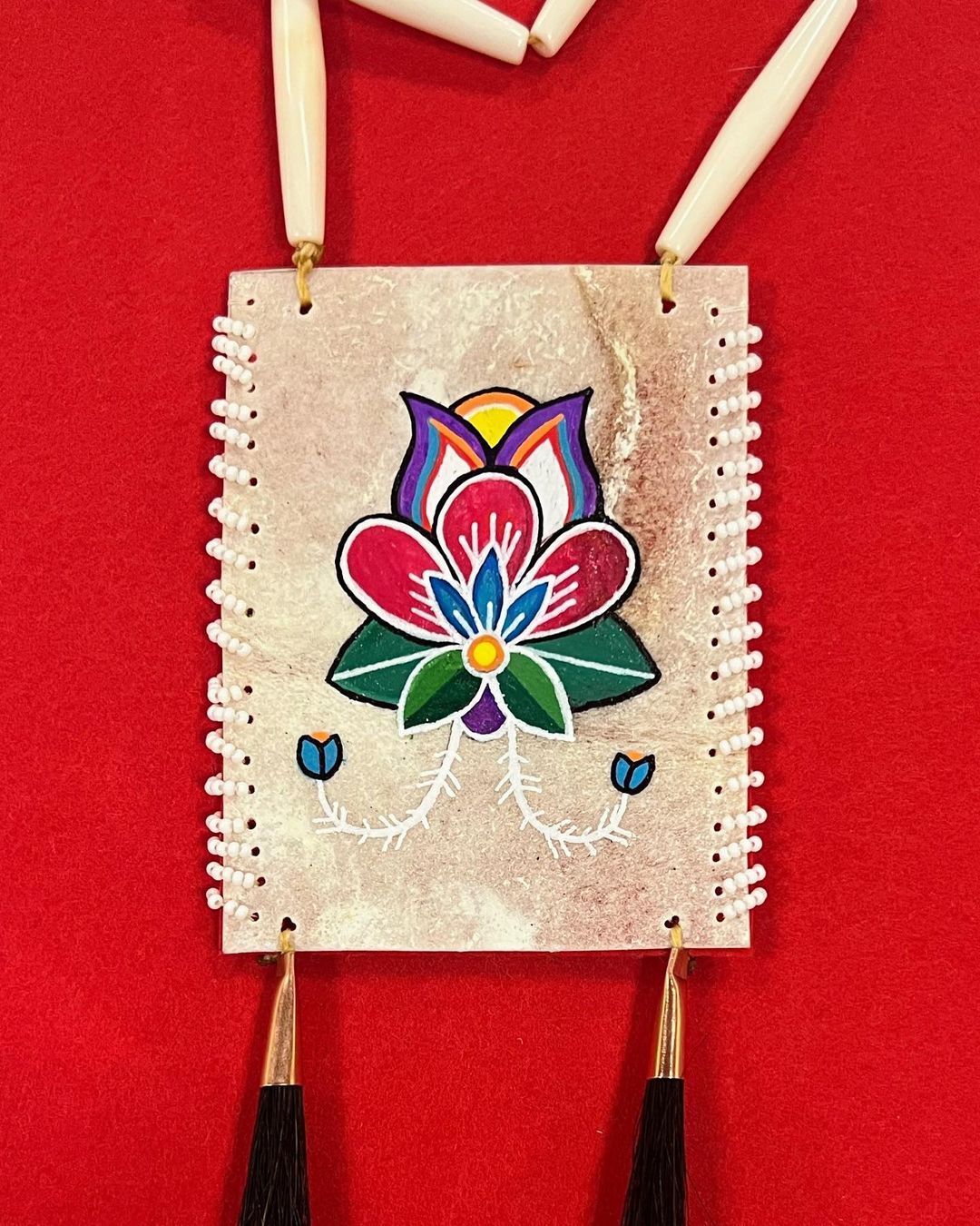 This beauty of a necklace is a new favourite. It’s made with painted parfleche and edged with beads. There are two horsehair embellishes, and the necklace string is made of bone piping. I absolutely love the natural scaring. I chose to paint on the “rough” side to showcase it.