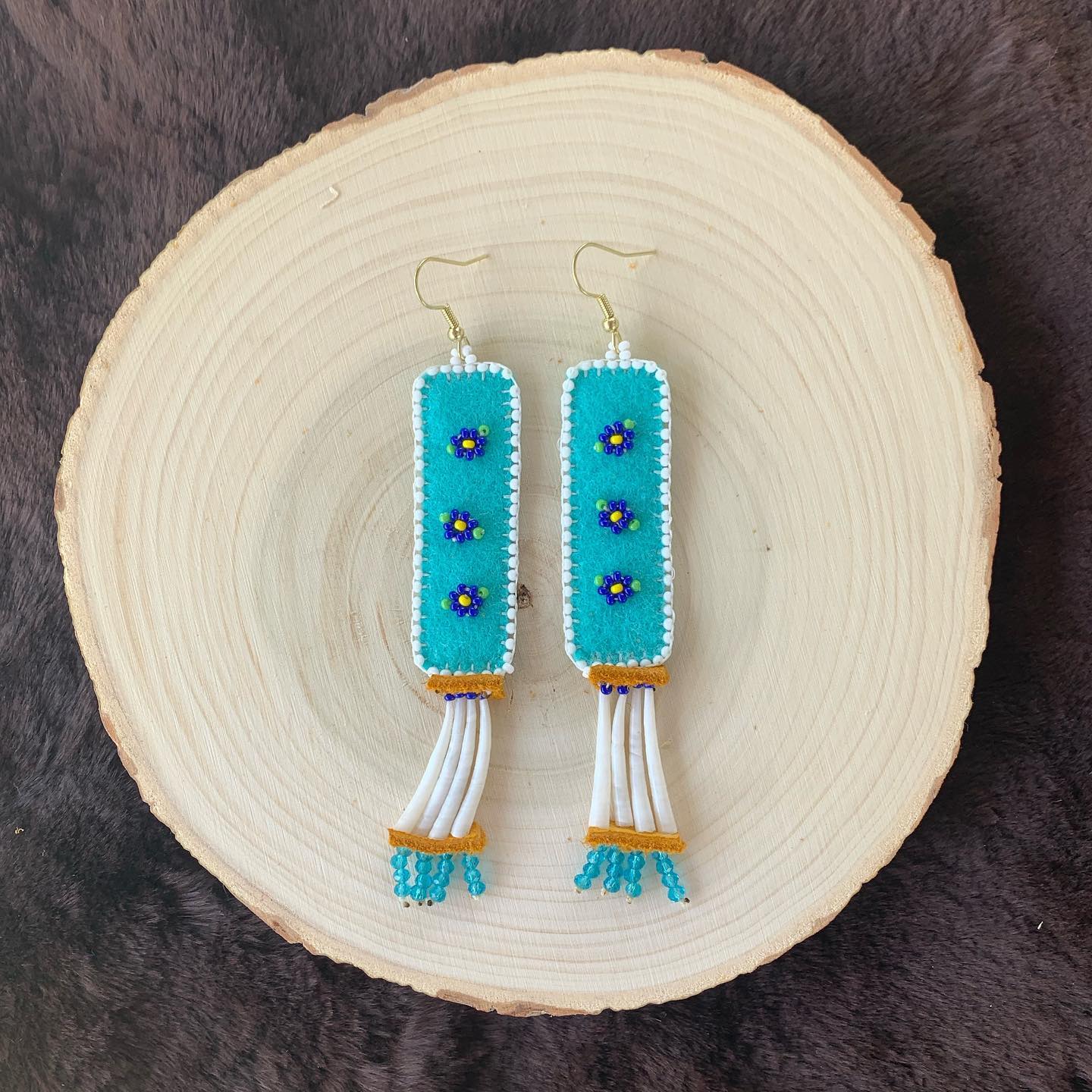 These cuties are beaded on turquoise felt and edged in glass beads. Single tiered dentalium rows are tipped in turquoise glass beads. Brass findings.