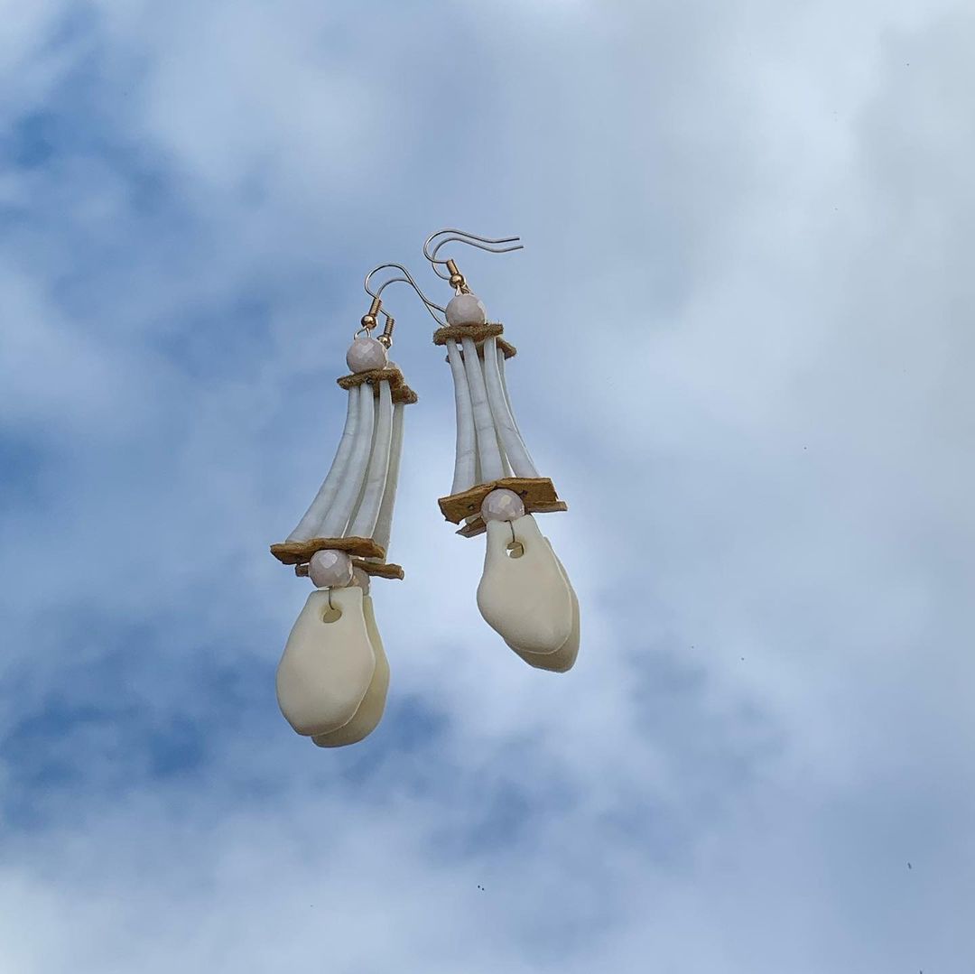 Long dentalium-tipped earrings with shiny cream-coloured glass beads. An imitation elk tooth hangs from the bottom.